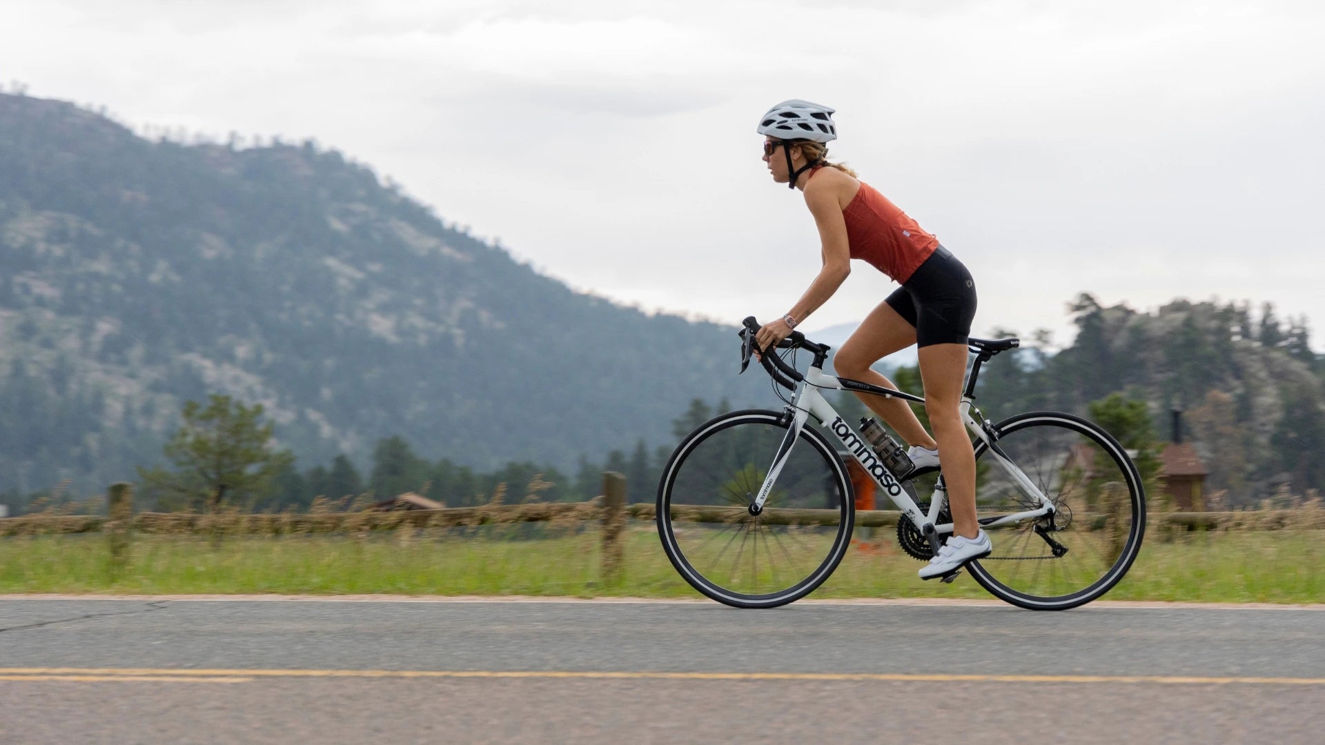 Cyclist riding a Tommaso road bike wearing white performance outdoor cycling shoes on a paved mountain road
